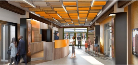 Building lobby entrance mock up. People talking to front desk associates. Family getting photos of the stadium. Security working the door. People entering the elevator to enter their office space.