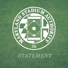 Image of the Maryland Stadium Authority logo, featuring a circular design with a baseball field illustration in the center and the text "Maryland Stadium Authority" around it. "Est. 1986" is written at the bottom, with "Statement" below the circle. The background is green, resembling grass.