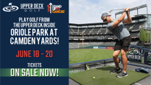 Outdoor golf event promotion at Oriole Park at Camden Yards. A person is swinging a golf club on an upper deck. Text highlights event dates: June 18-20. Logos of Upper Deck Golf and Stand Up To Cancer are displayed. Tickets are on sale.